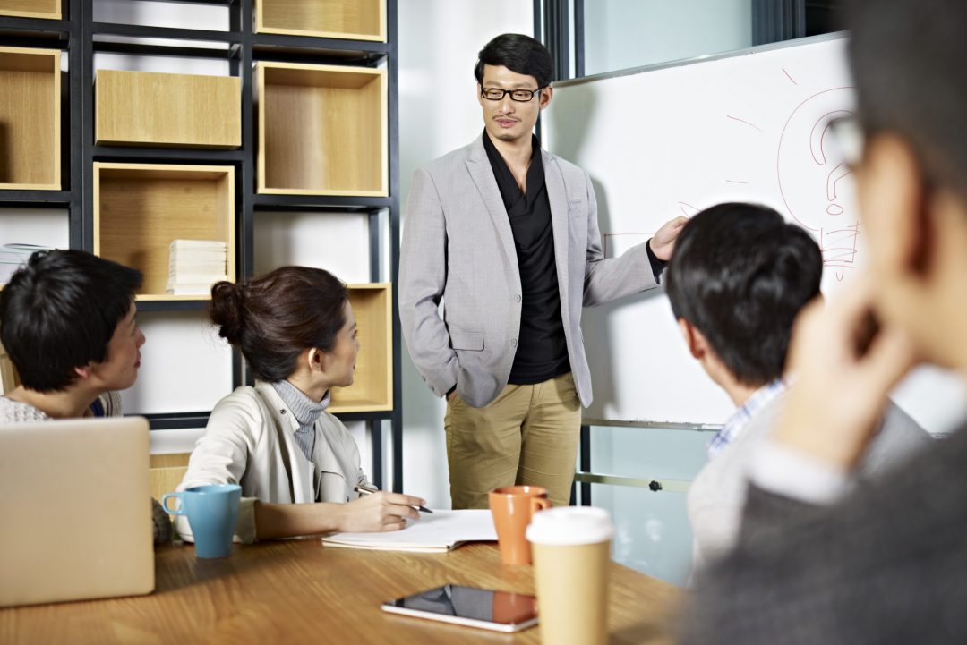 young asian business executive facilitating a discussion or brainstorm session in meeting room.