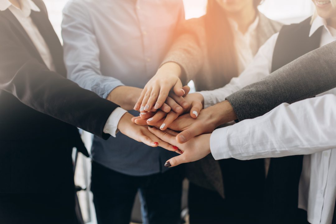 Close up top view of young business people putting their hands together. Stack of hands. Unity and teamwork concept.